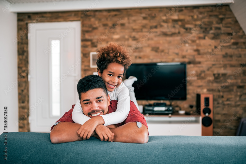 Loving african american girl and her dad at home, looking at camera.