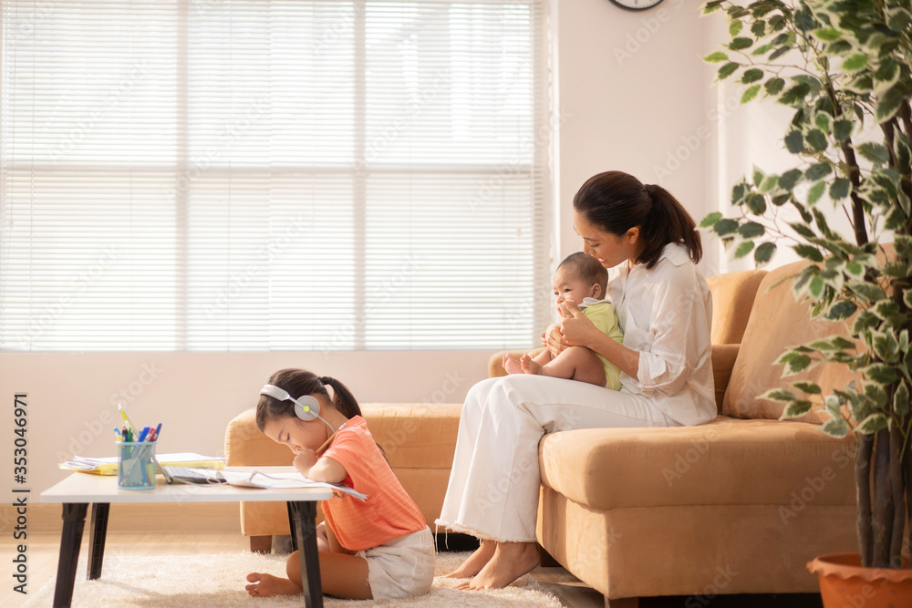 Her daughter is studying online at home. Her mother is with a baby