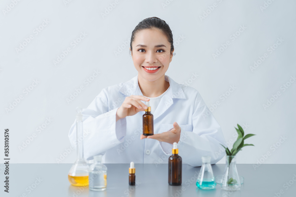 Female dermatologist holding bottle of skin care product over table, closeup