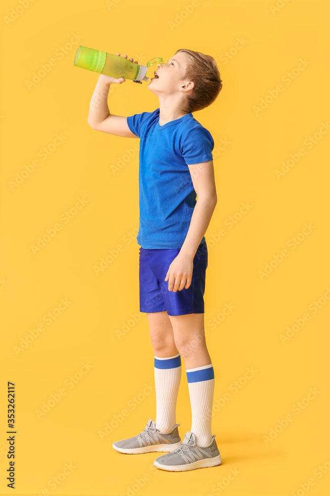 Sporty little boy with water on color background