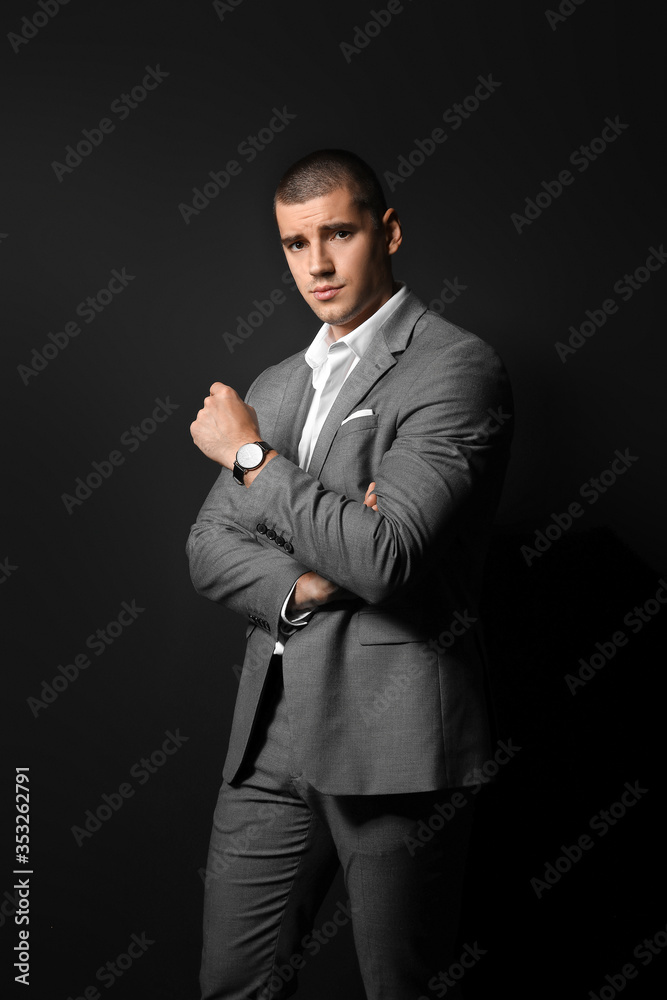 Handsome young man in elegant suit on dark background