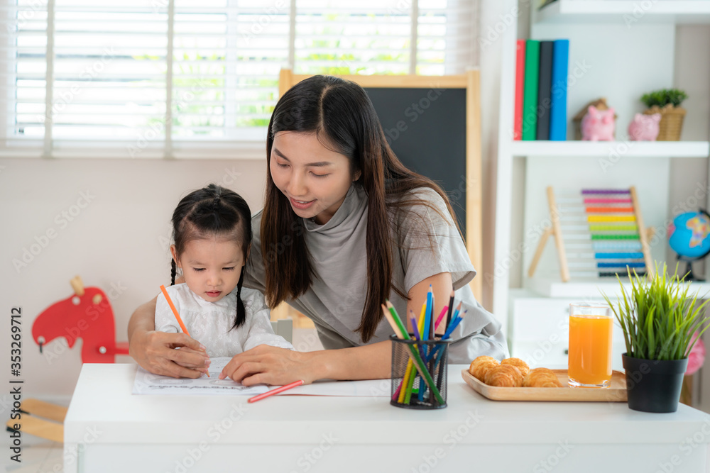 Asian kindergarten student girl with mother painting picture in book with color pencil at home, Home