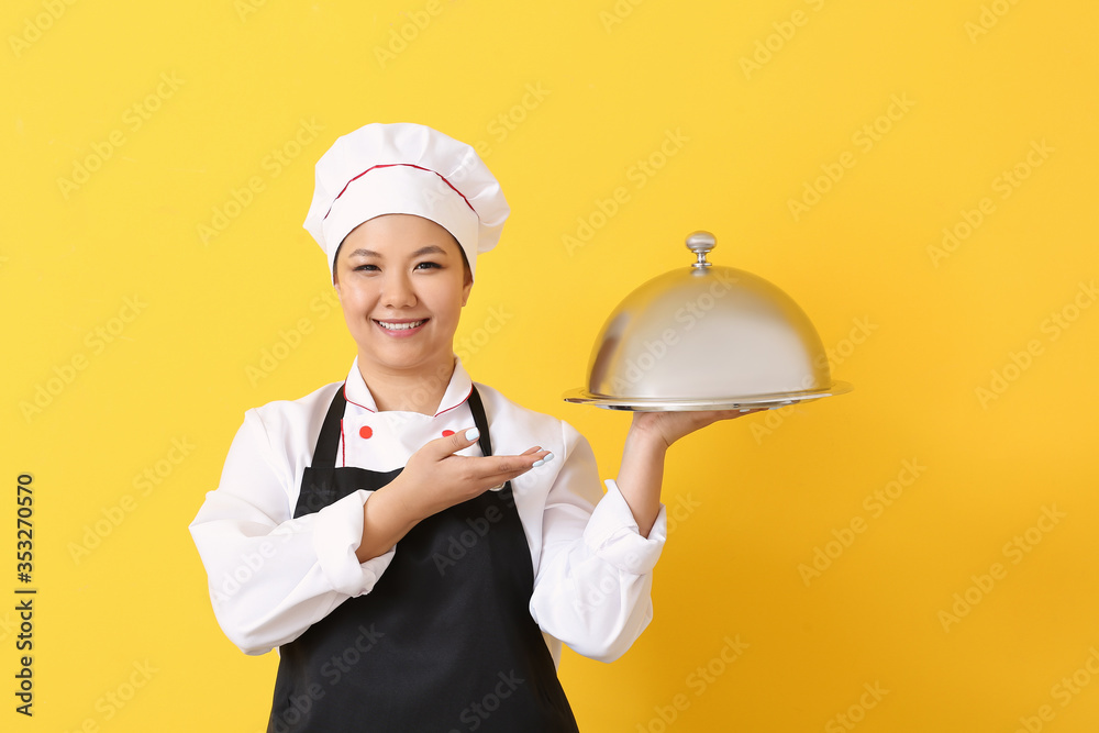 Beautiful Asian chef with tray on color background