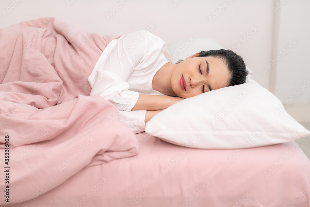 Young beautiful woman sleeping in her bed and relaxing in the morning