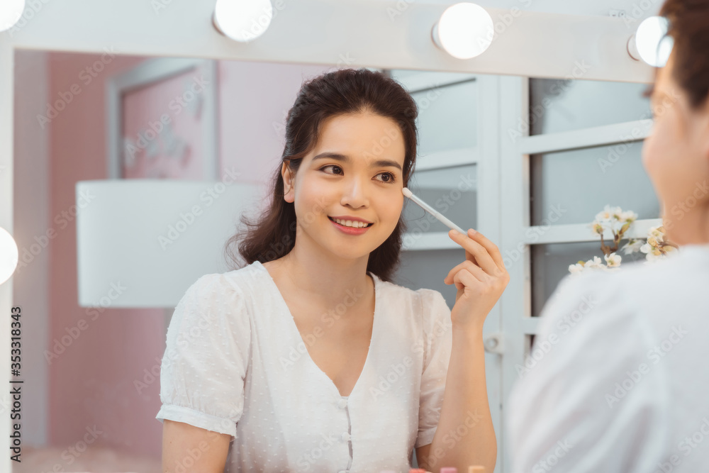 令人惊叹的年轻女子在镜子前化妆。化妆塔附近美丽女孩的肖像