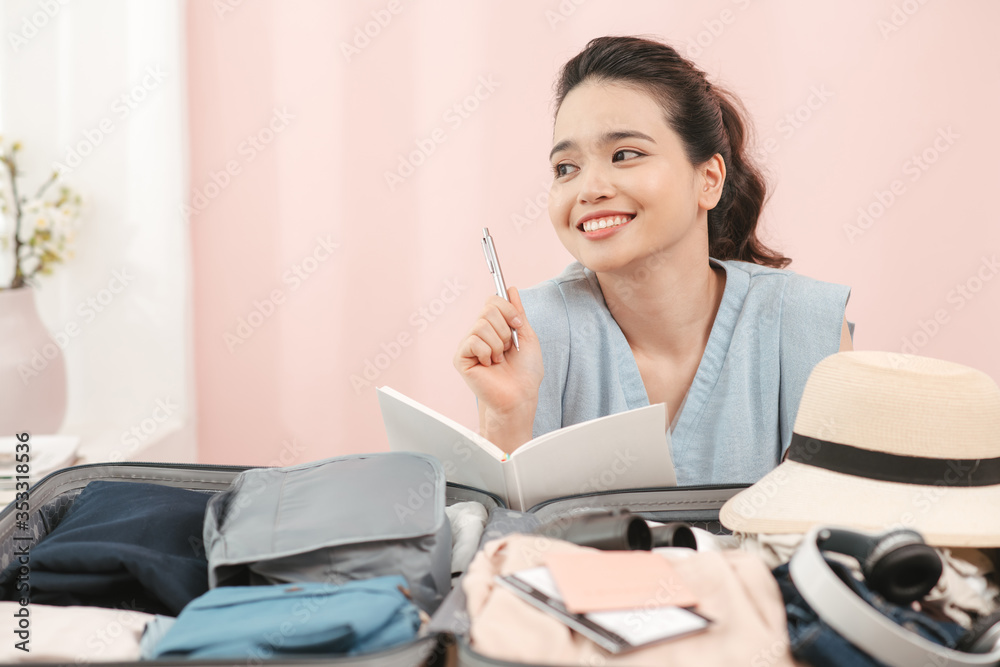 young asian pretty woman traveler smiling prepare and packing clothes into suitcase for holiday vaca