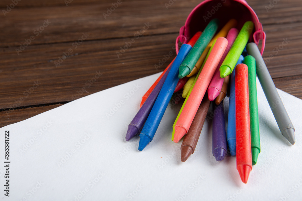 colored crayons and blank page on the wooden table