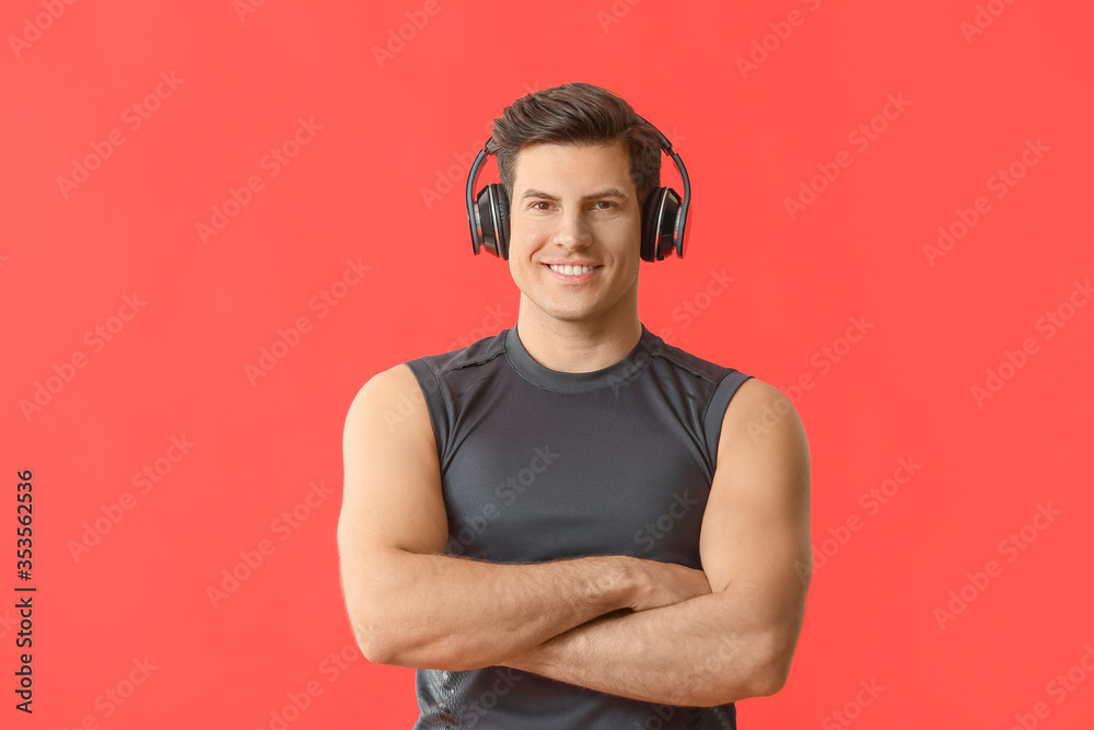 Sporty young man listening to music on color background