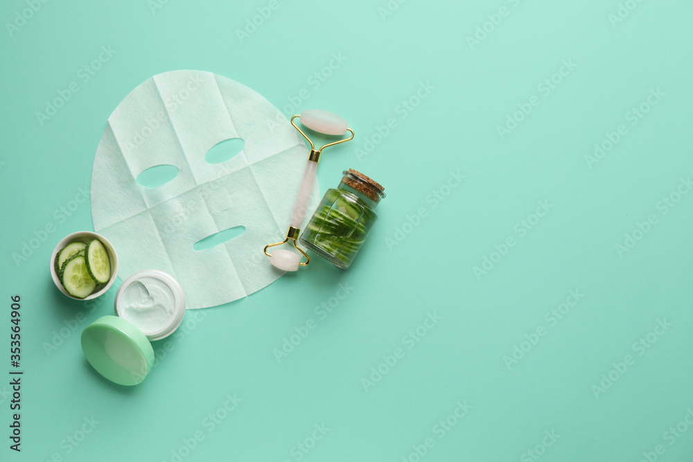 Composition with fabric facial mask, cream and cucumber on color background