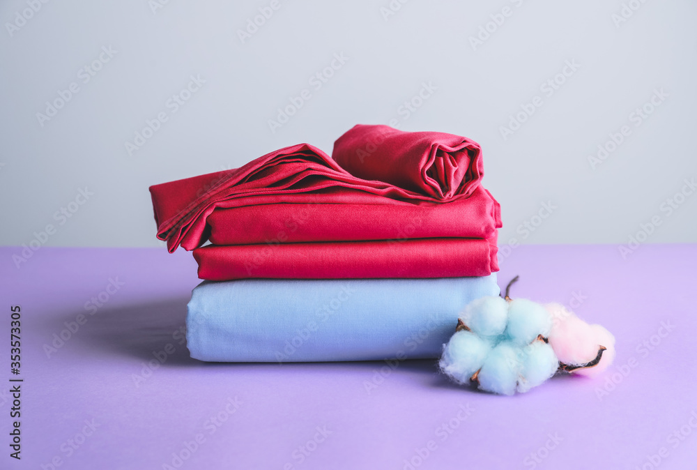 Stack of clean bed sheets on color background