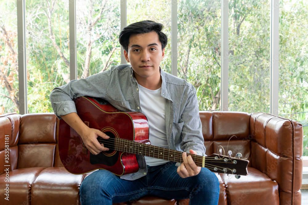 Young guitar player holding his guitar at home. Music and song concept.