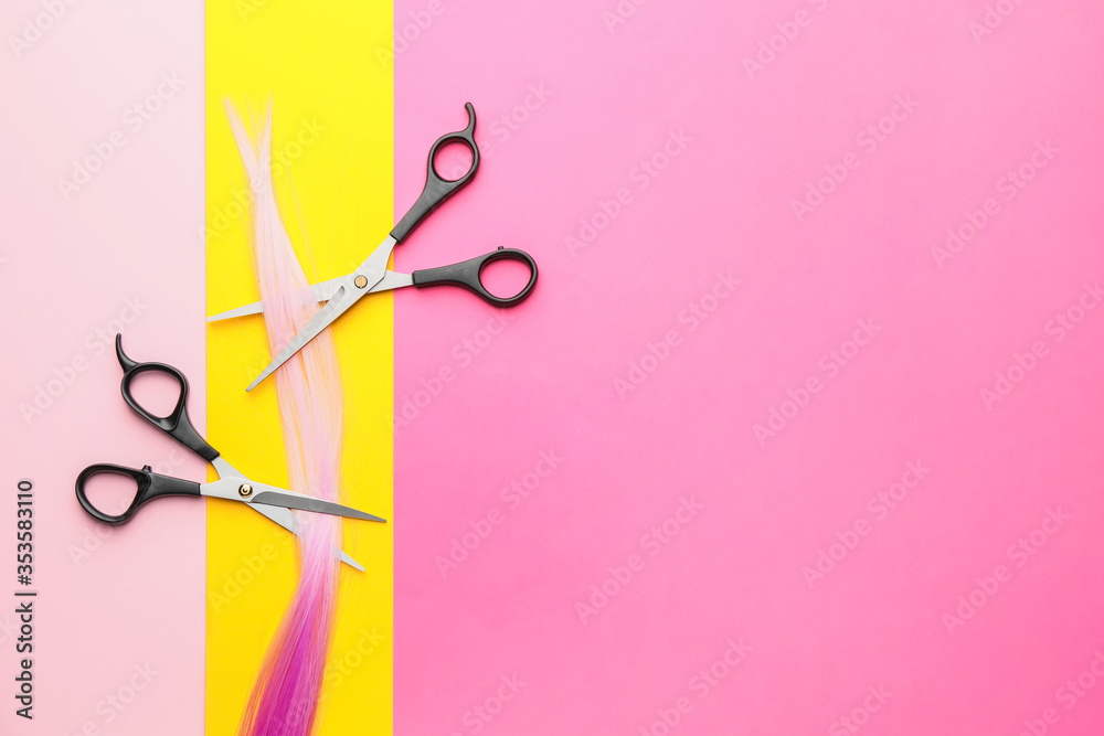 Hairdresser scissors with strand on color background