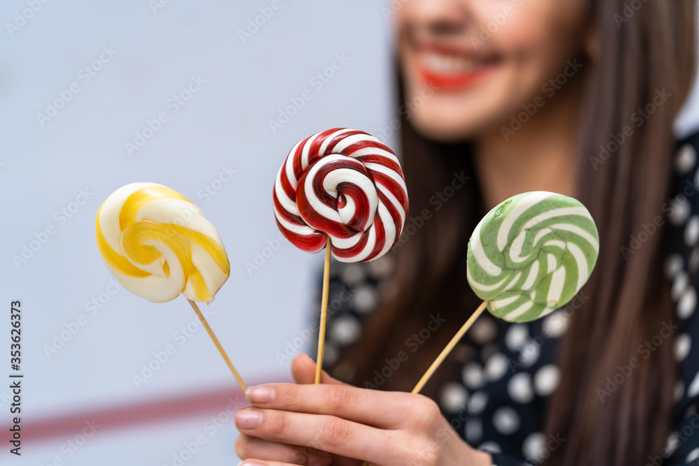 Hand holding lollipops over blurred background of woman face.