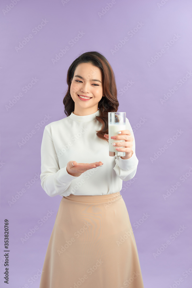 Smiling woman holding a glass of milk against a purple background