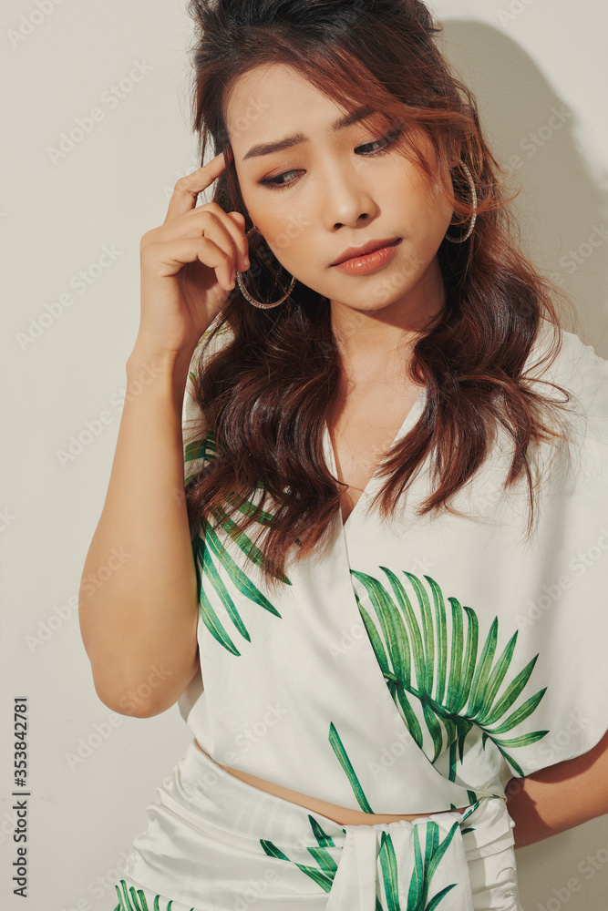 Serious young Asian woman look away in tropical shirt on white background