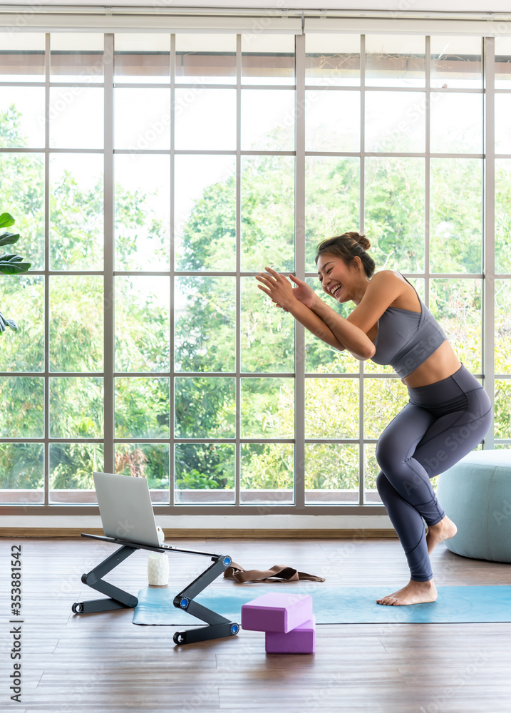 Young good looking woman having fun practising on online course yoga for beginner at home