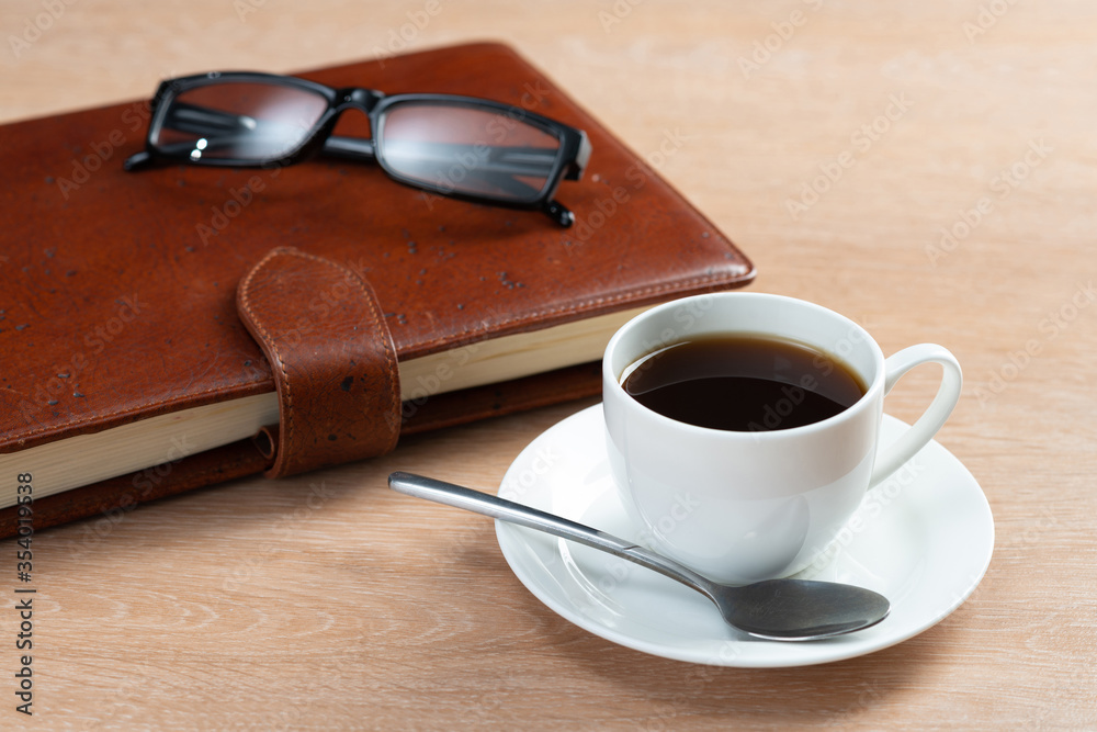 Brown leather notebook and glasses on table