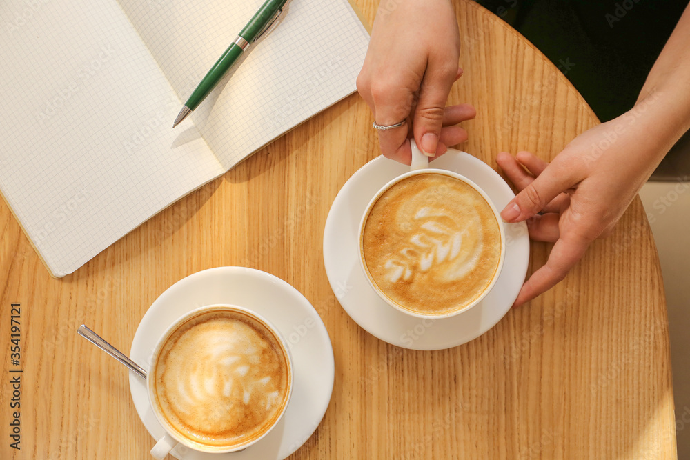 Woman drinking tasty coffee at table in cafe