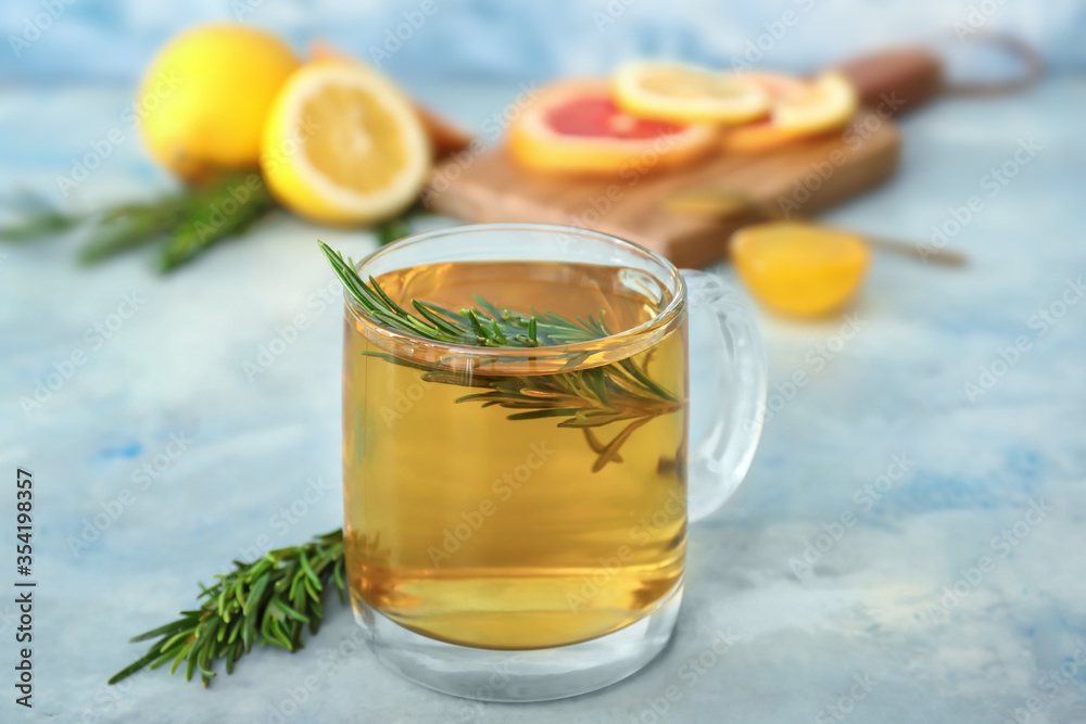 Cup of hot tea with rosemary on color background