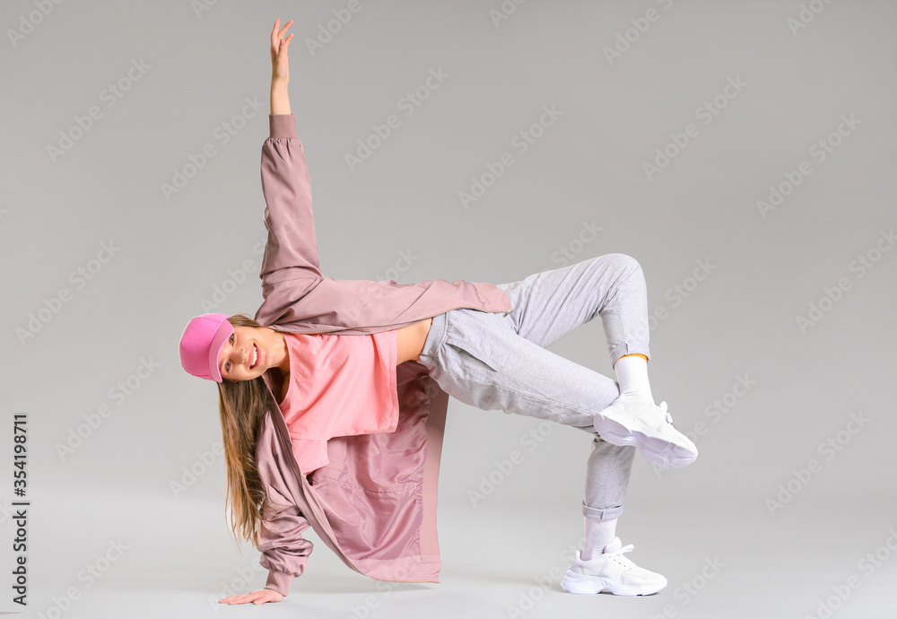 Young female hip-hop dancer on grey background