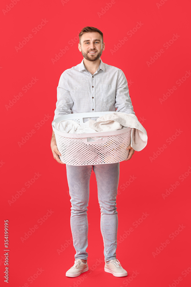 Young man with laundry on color background