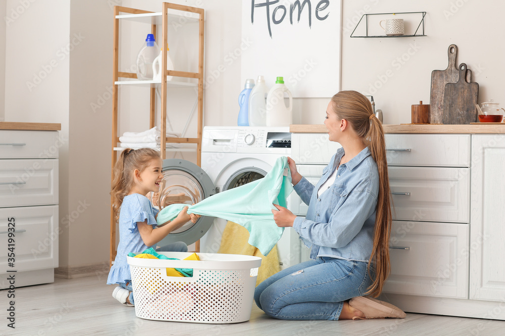 Mother and little daughter doing laundry at home