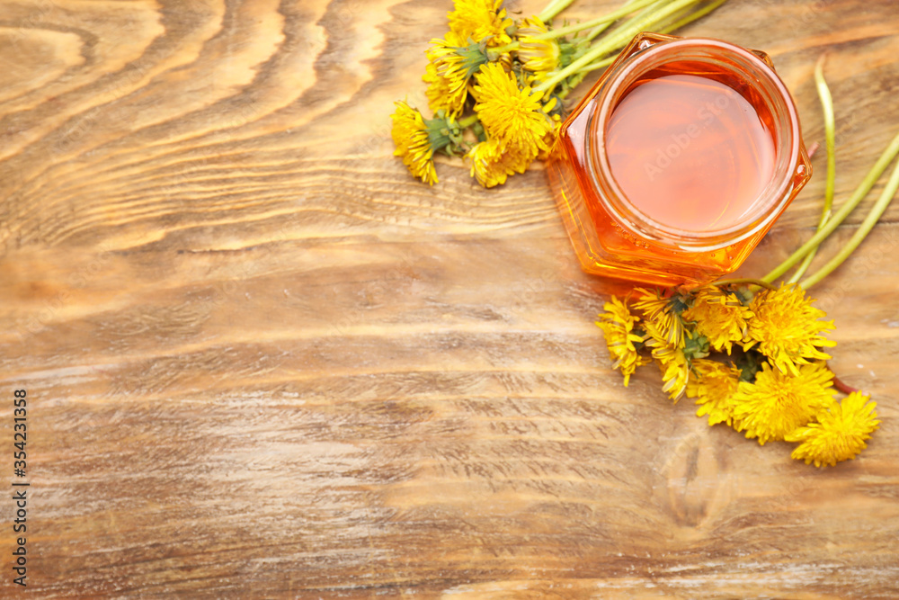 Jar of sweet dandelion honey on wooden background