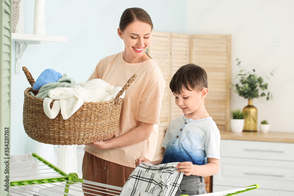 年轻女子带着她的小儿子在家洗衣服