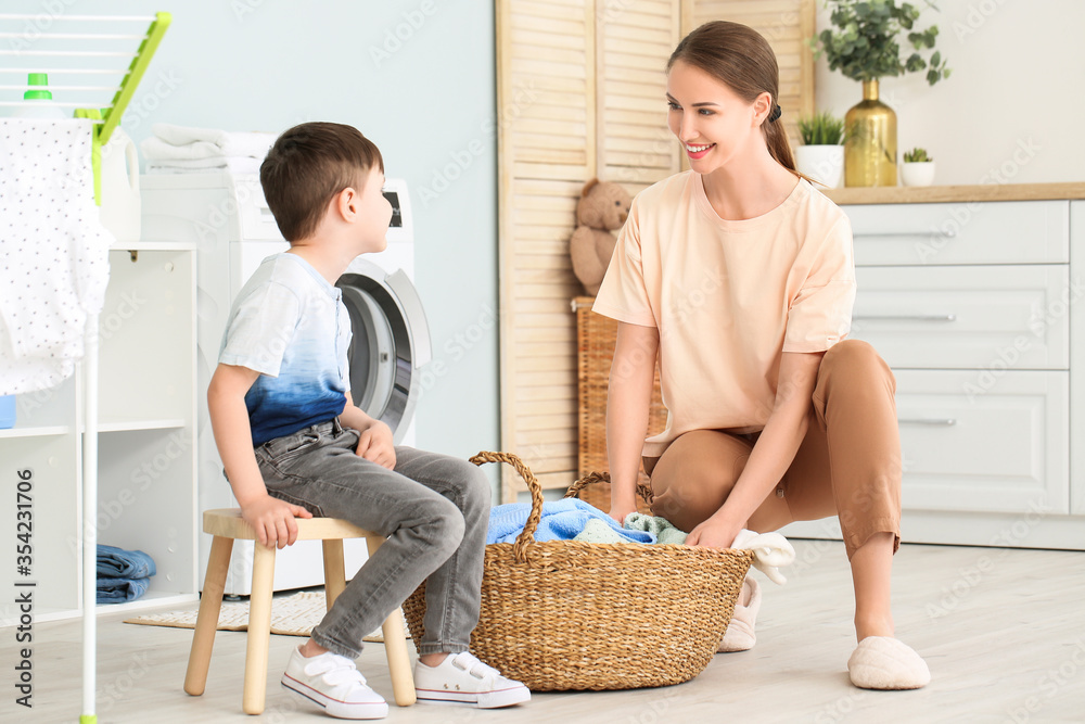 Young woman with her little son doing laundry at home