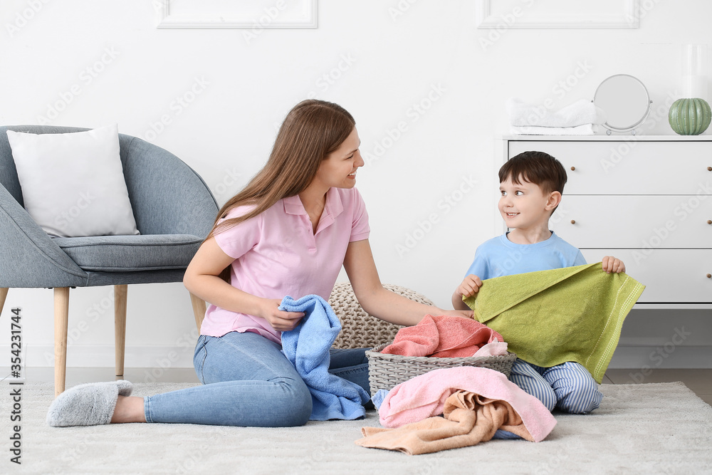 Young woman and her little son with clean laundry at home