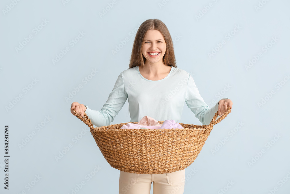 Young woman with clean laundry on color background