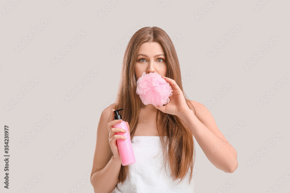 Beautiful young woman with shower gel on light background