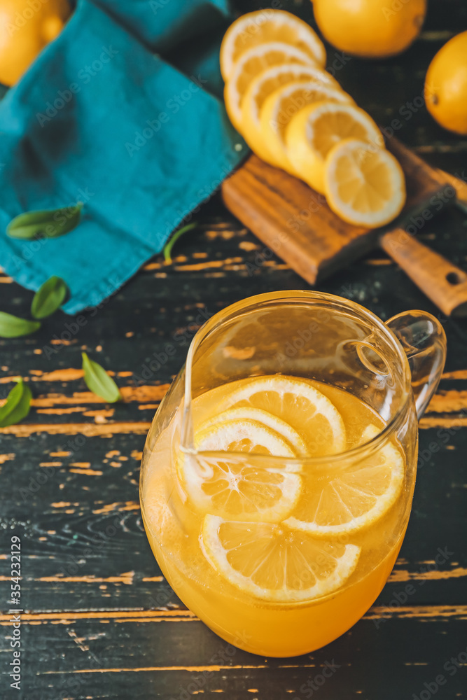 Jug of fresh lemonade on dark wooden table