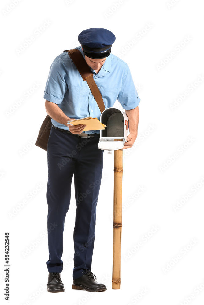 Handsome young postman putting letters in mail box on white background