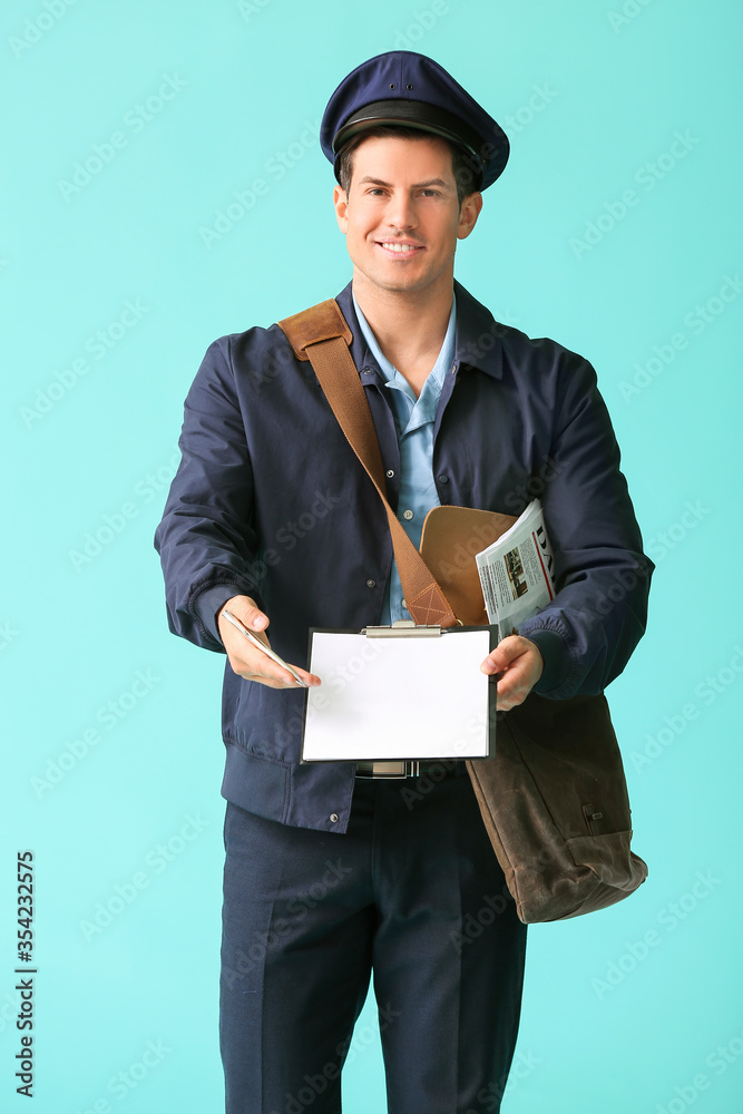 Handsome young postman on color background