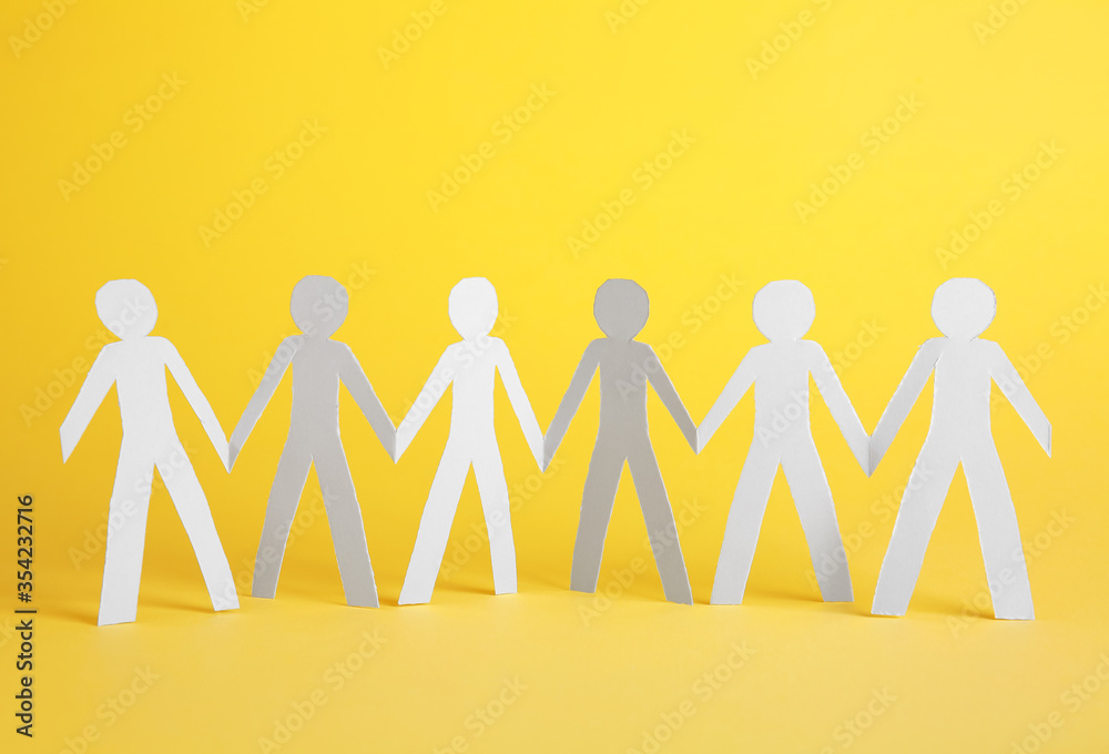 Paper human figures holding hands on color background. Unity concept