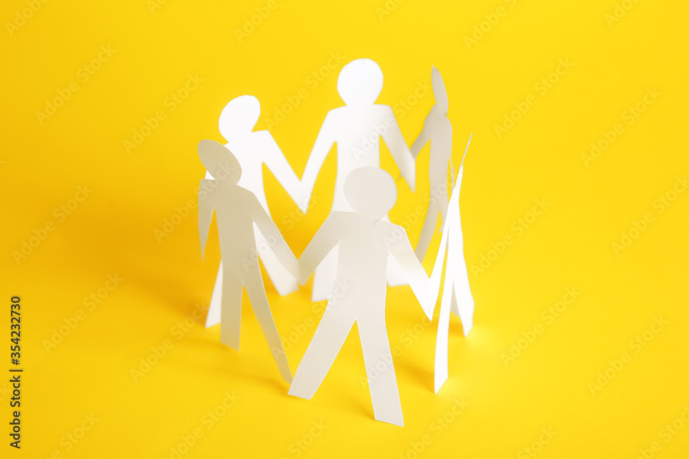 Paper human figures holding hands on color background. Unity concept