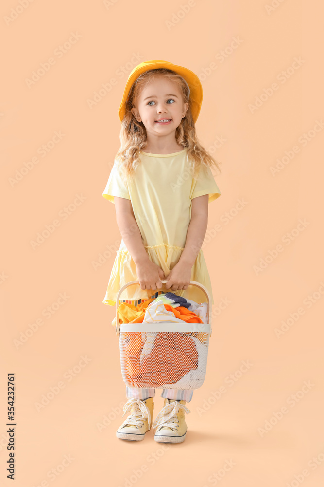 Cute little girl with dirty laundry on color background