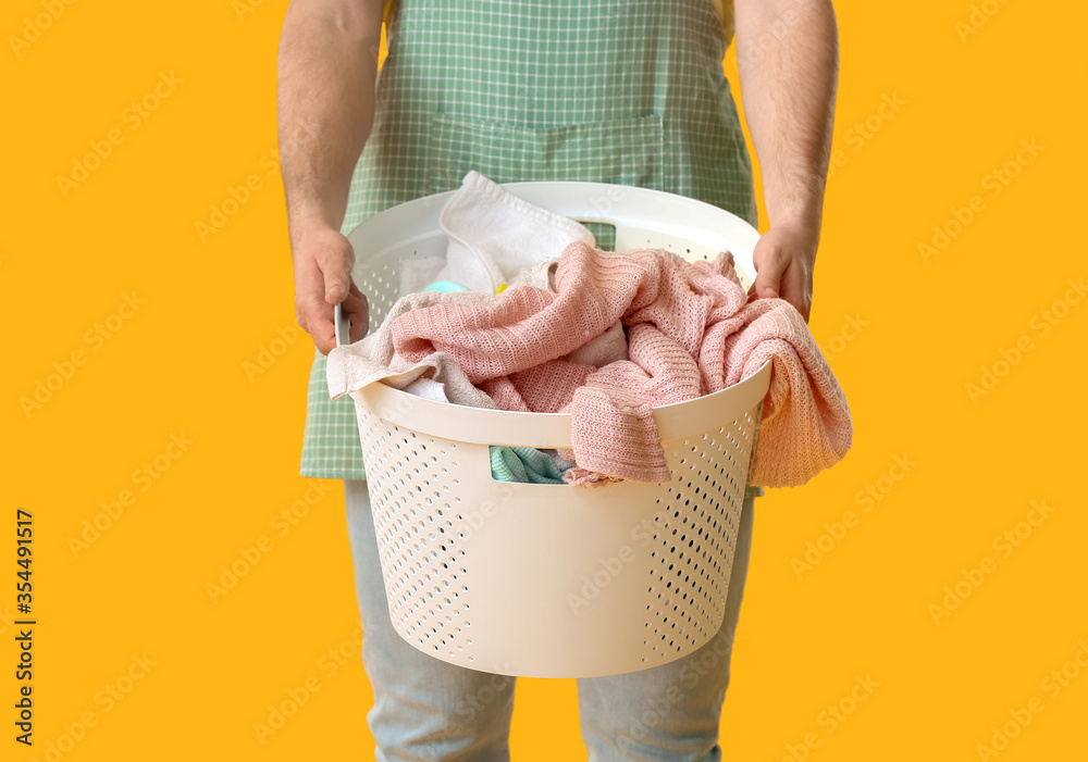 Young man with laundry on color background