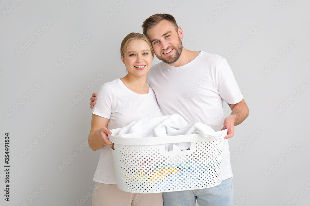 Couple with laundry on grey background