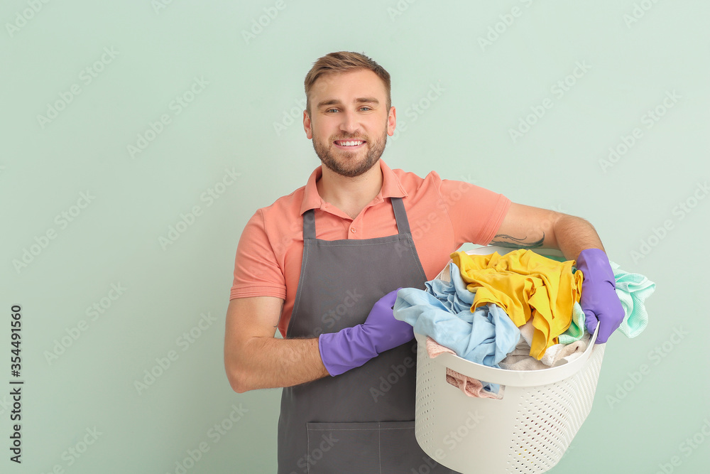 Young man with laundry on grey background