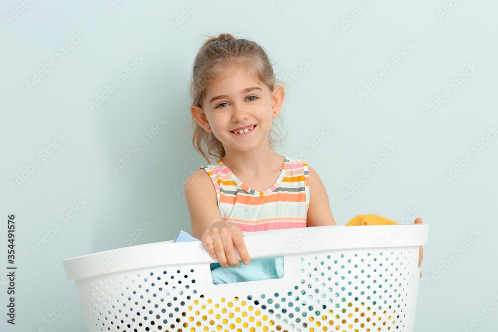 Little girl with laundry on grey background