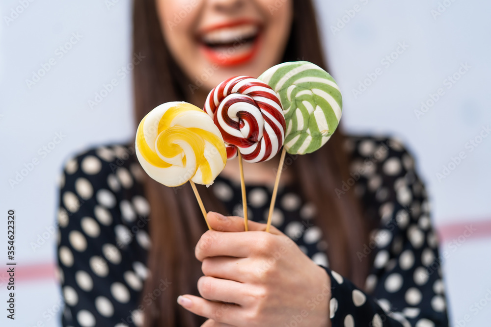 Female hand with sweet lollipops on blurred background. Hand holding lollipop isolated on white back