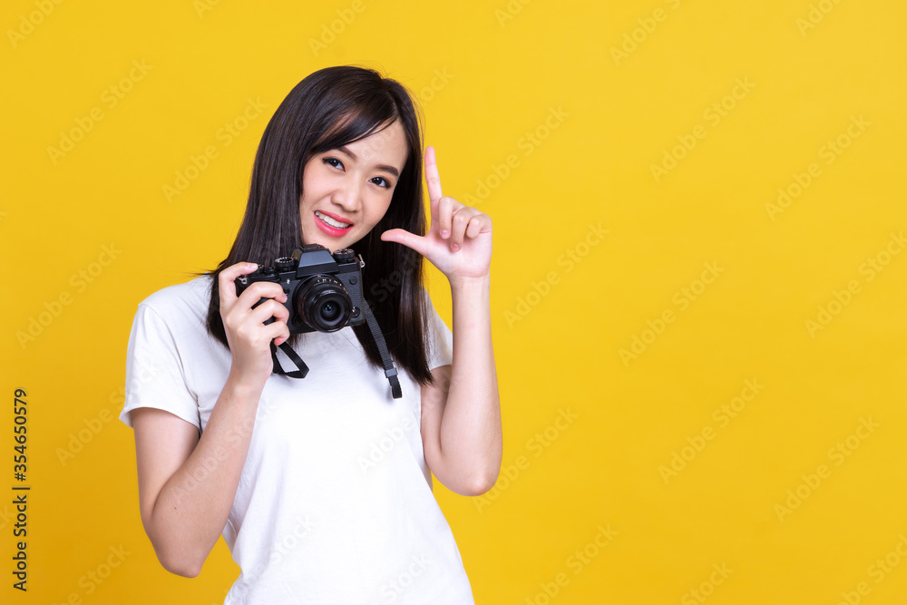 Portrait photo of Asian smiling pretty girl in white shirt taking photo on camera isolated over orra