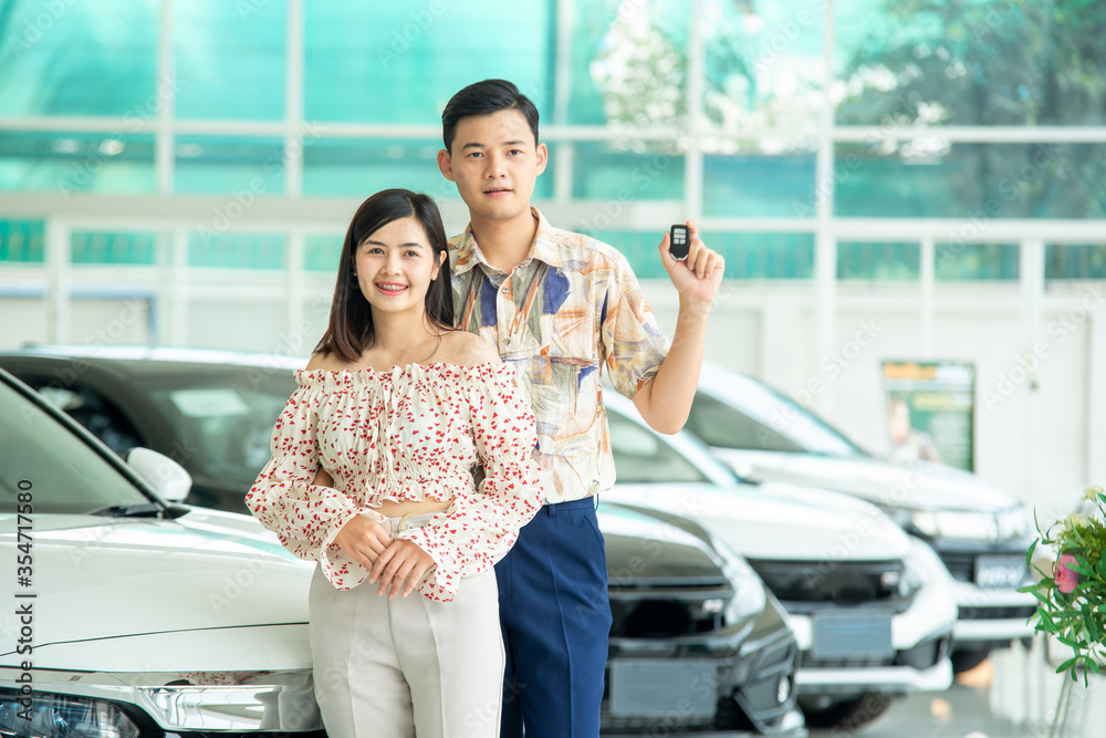 夫妻在汽车经销店买车，销售人员在汽车展厅卖车。