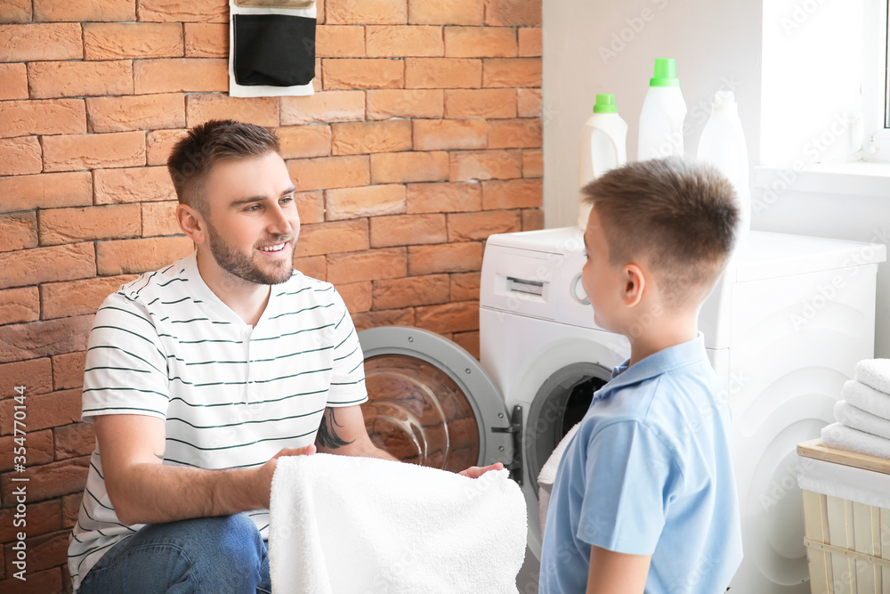 Man and his little son doing laundry at home