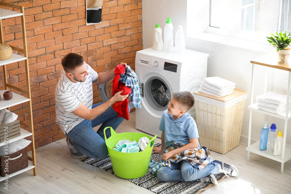 Man and his little son doing laundry at home