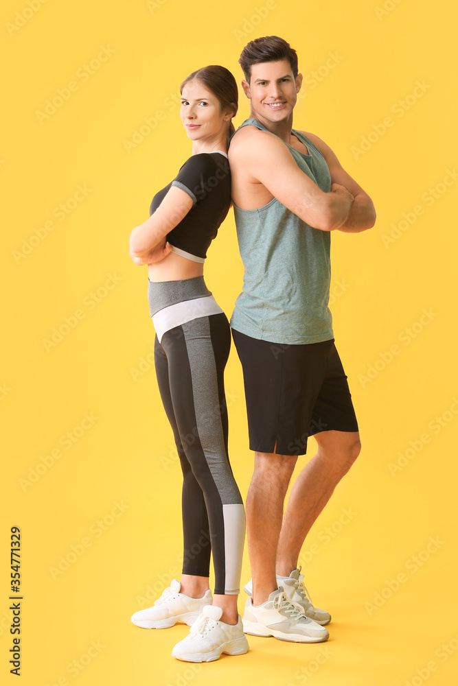 Sporty young couple on color background