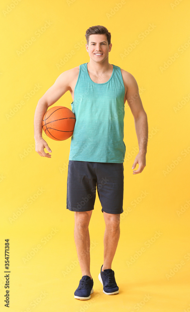 Sporty young man with ball on color background