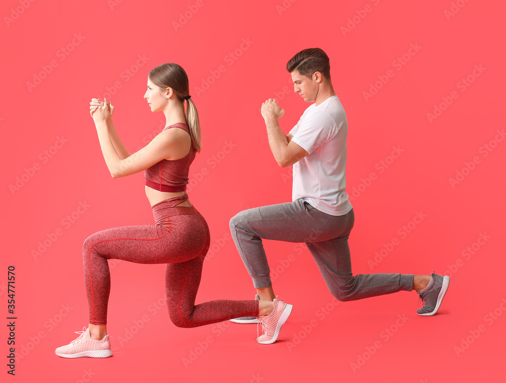 Sporty young couple training on color background